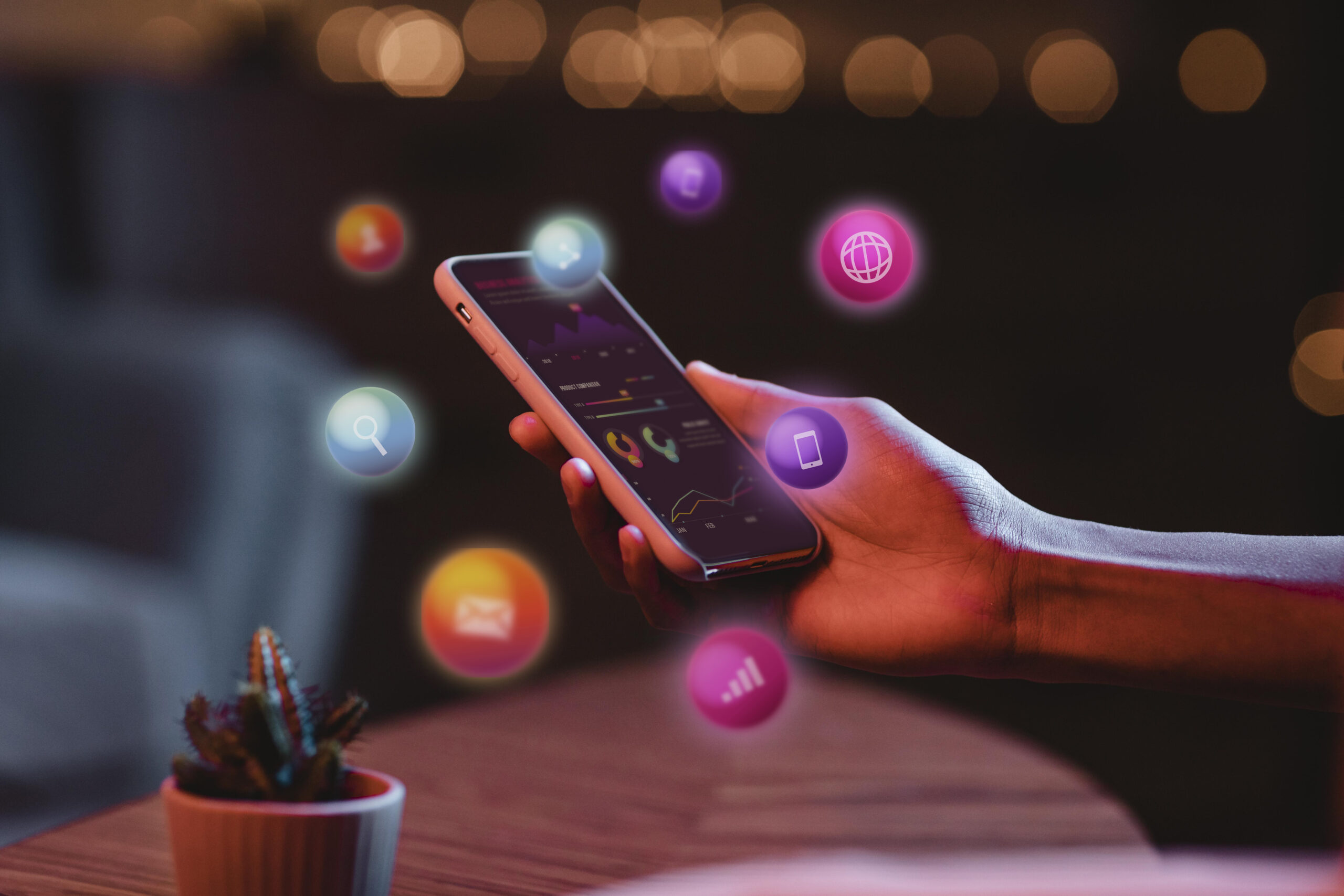 Mão segurando um smarphone e com ícones saindo pela tela representando o marketing digital.